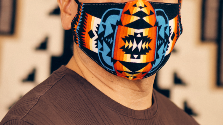 A Native community members wears a colorful mask under text: Be a Good Relative.